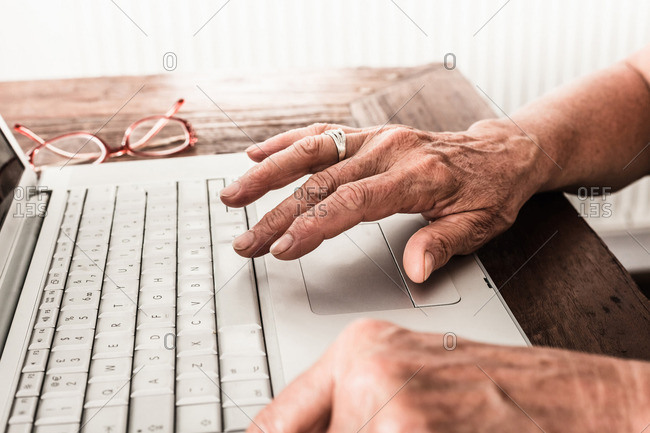 Close up of older mans hands on laptop