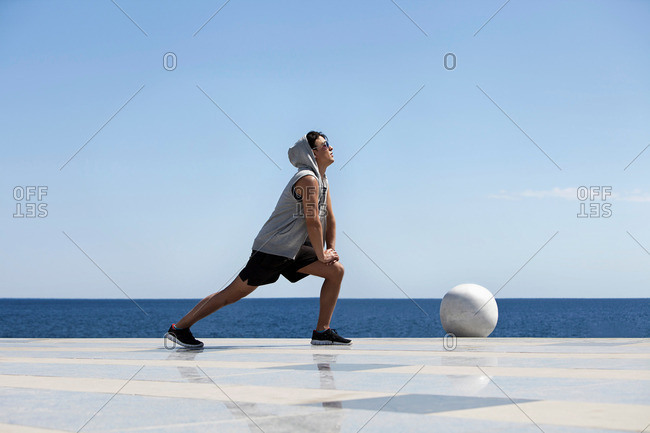 Young man stretching near ocean
