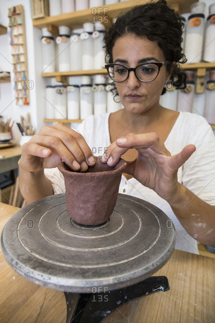 Woman sculpting a cup with clay in a ceramic workshop