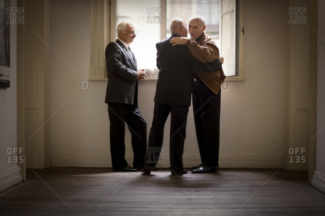 Senior businessmen hug during a meeting.