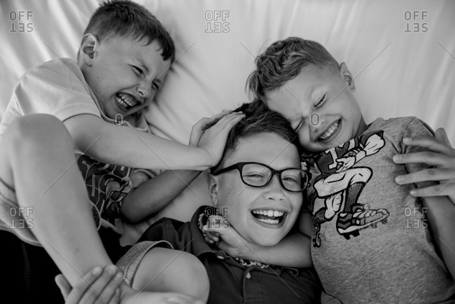 Three brothers wrestling on bed