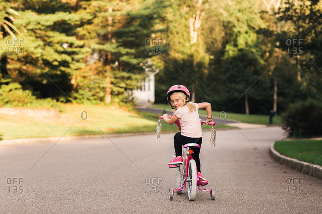 Little girl riding pink bike with training wheels