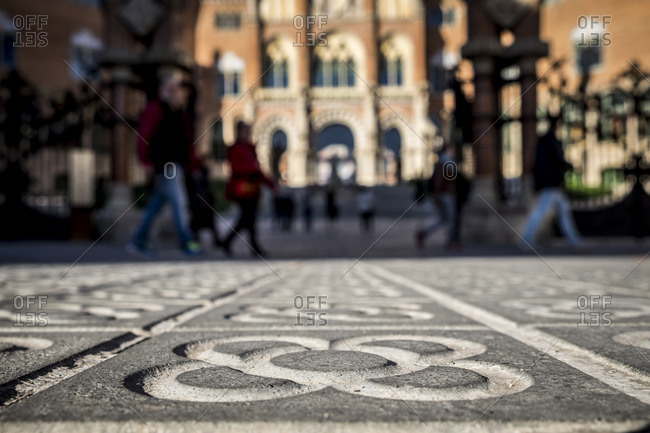 People walking on decorative tiled pavement at Hospital de Sant Pau, Barcelona, Spain