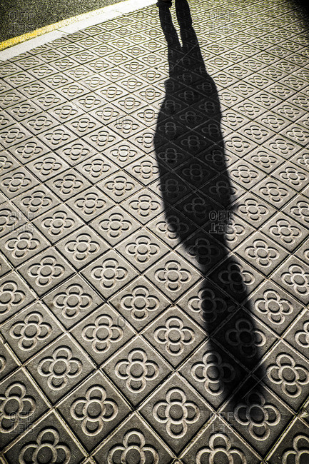 Shadow of person on classic tile sidewalks of the city of Barcelona, Spain