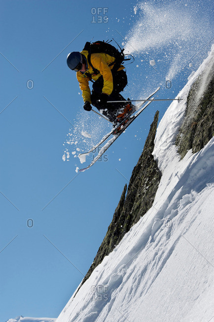 Skier jumping over steep mountain face