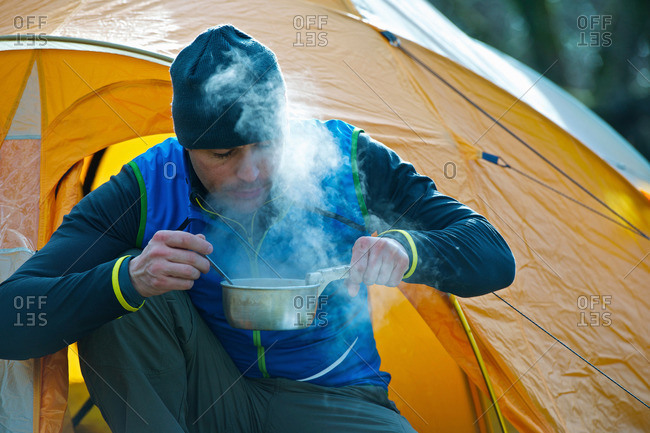 Man cooking food by camping tent