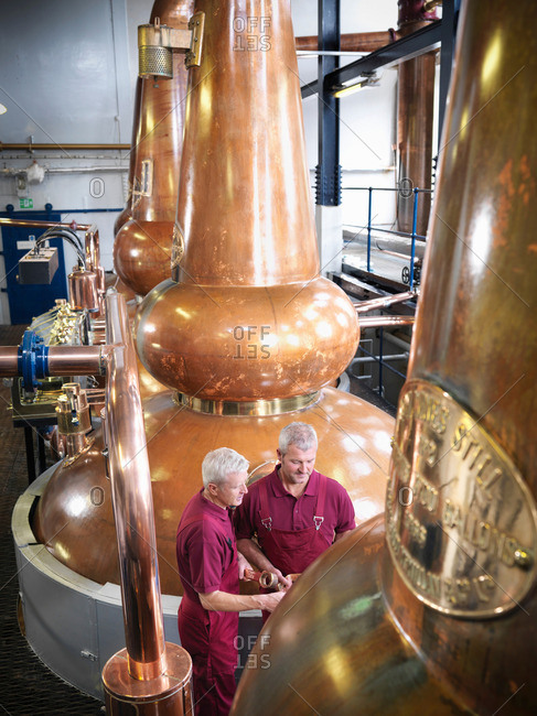Workers checking whisky stills in distillery