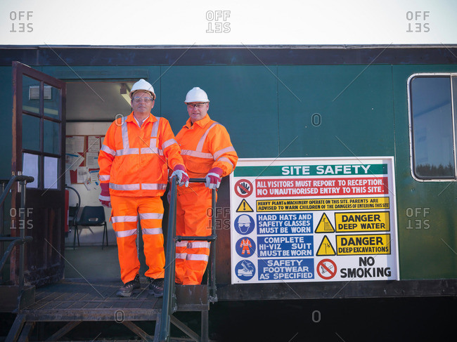Portrait of opencast coalminers standing next to Health and Safety sign