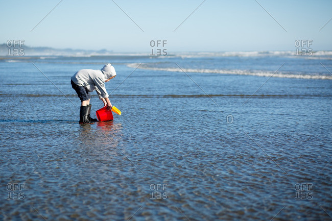 Boy catching water in a pail on a beach