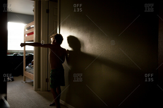 Boy standing in a dark hallway practicing martial arts moves