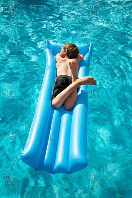Boy (7-9) lying on inflatable air bed in pool