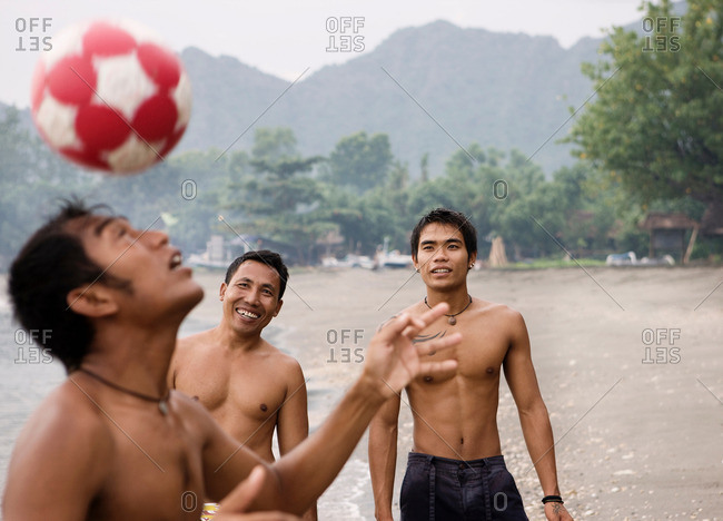 Guys playing football on beach