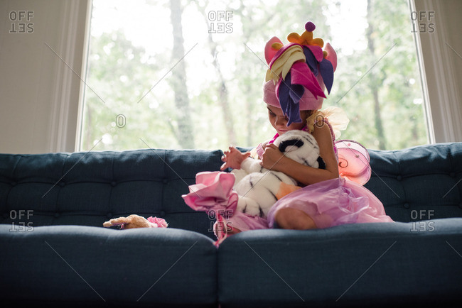 Little girl hugging her stuffed animals on a couch