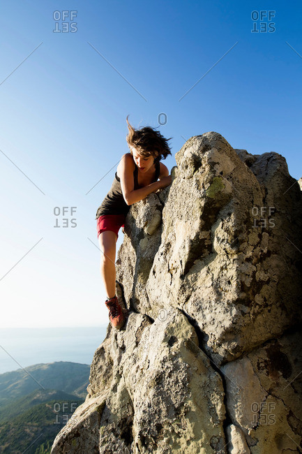 Hiker climbing rocks on hill