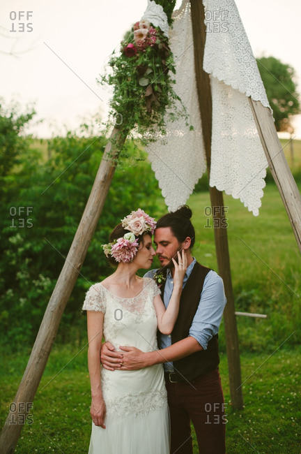 Bride and groom embraced under wooden arbor