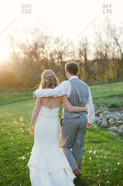 Bride and groom walking with arms around each other in the countryside