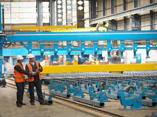 Engineers inspect laser flat bed steel cutting machine in ship yard