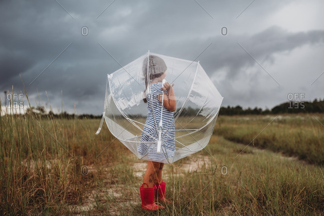 Little girl holding clear umbrella in a country field