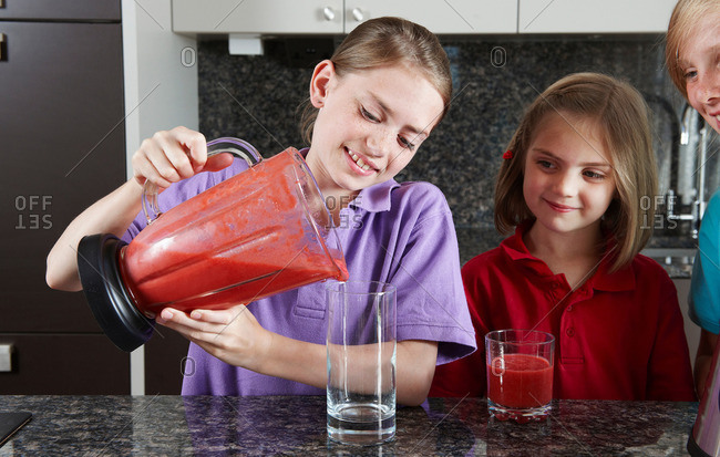 Girls pouring fruit juice from blender