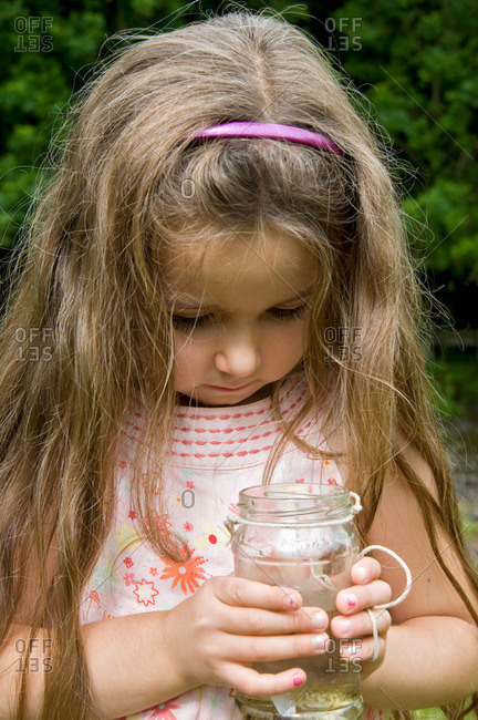 Girl looking at fish caught in jam jar