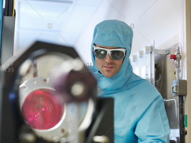 Male scientist in protective clothing and goggles working with a laser in a laboratory