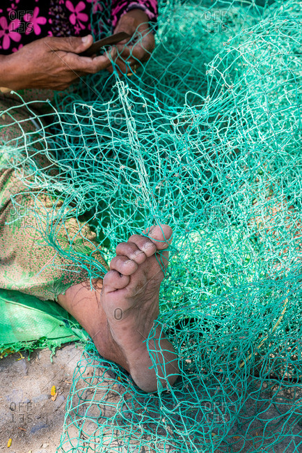 Foot of woman repairing fishing net
