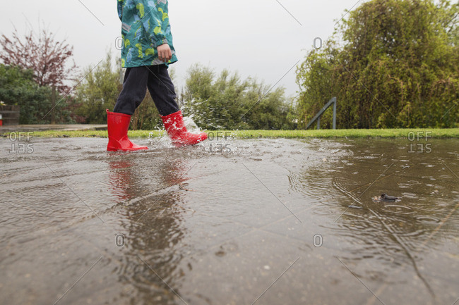 Child walking in rain water on ground