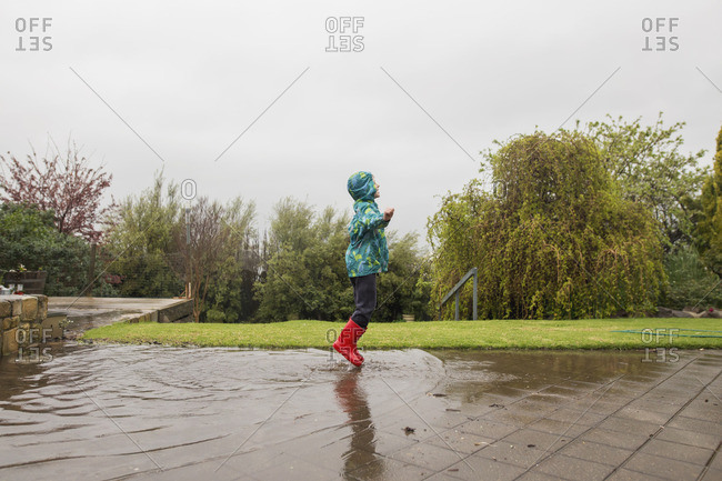 Child jumping in rain puddles