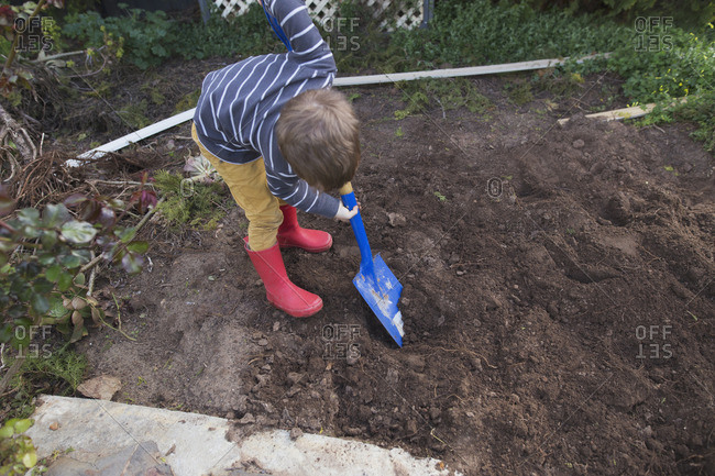 Boy digging in yard with shovel