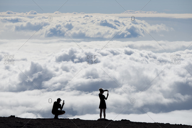 People silhouetted against the clouds at a lookout point in Haleakala National Park, Maui, Hawaii