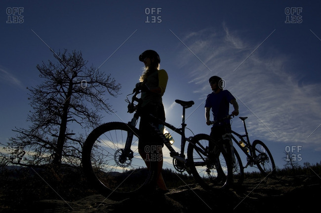 Silhouette of a couple stopping to take in the view while mountain biking near Kamloops, British Columbia, Canada