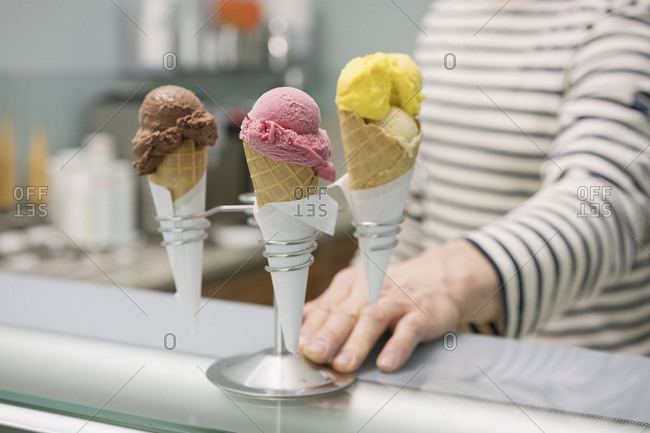 Midsection of man by various ice cream cones in stand at store