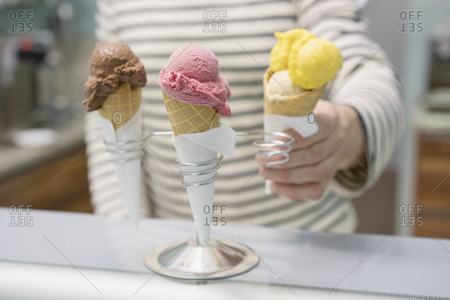 Midsection of man holding ice cream cone by stand at store