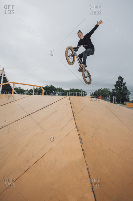 Teenager performing stunt on BMX bicycle at skateboard park