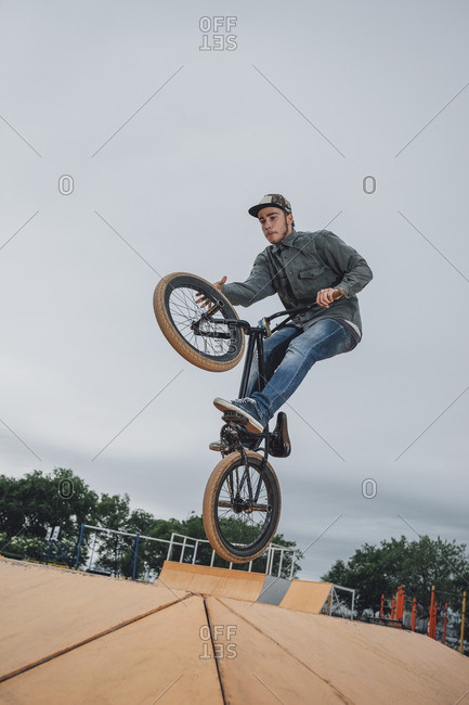 Teenager performing stunt at skateboard park against sky