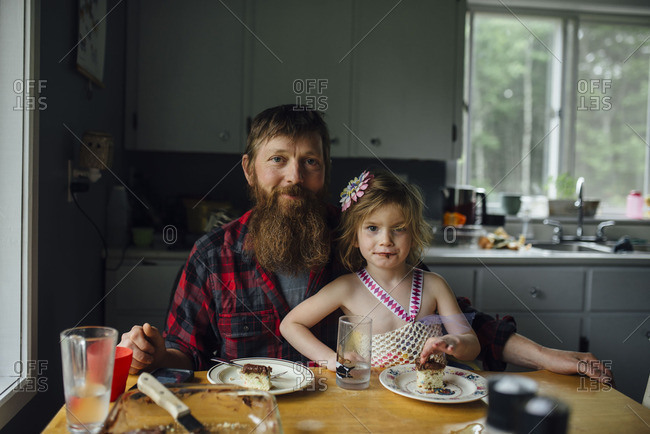 Father and daughter sitting together at the table eating cake
