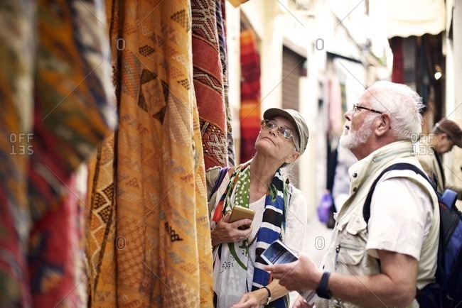 Senior couple shopping for rugs in outdoor market