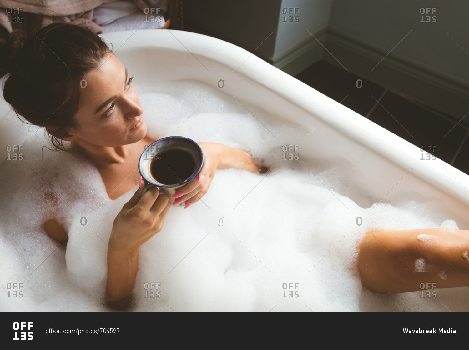 Худышка с длинными волосами обливается водой в ванне джакузи