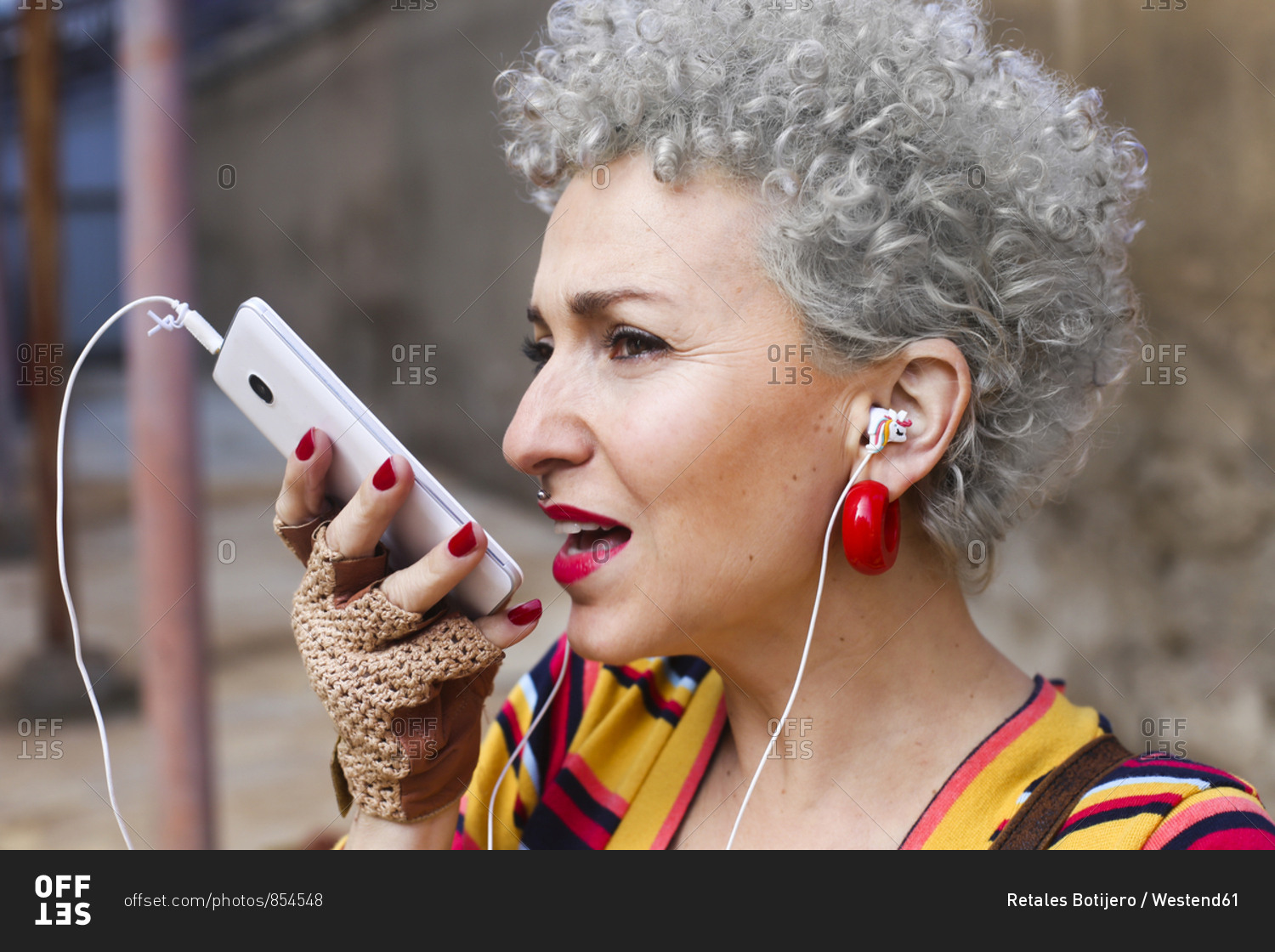 Portrait Of Pierced Mature Woman With Grey Curly Hair Using Earphones