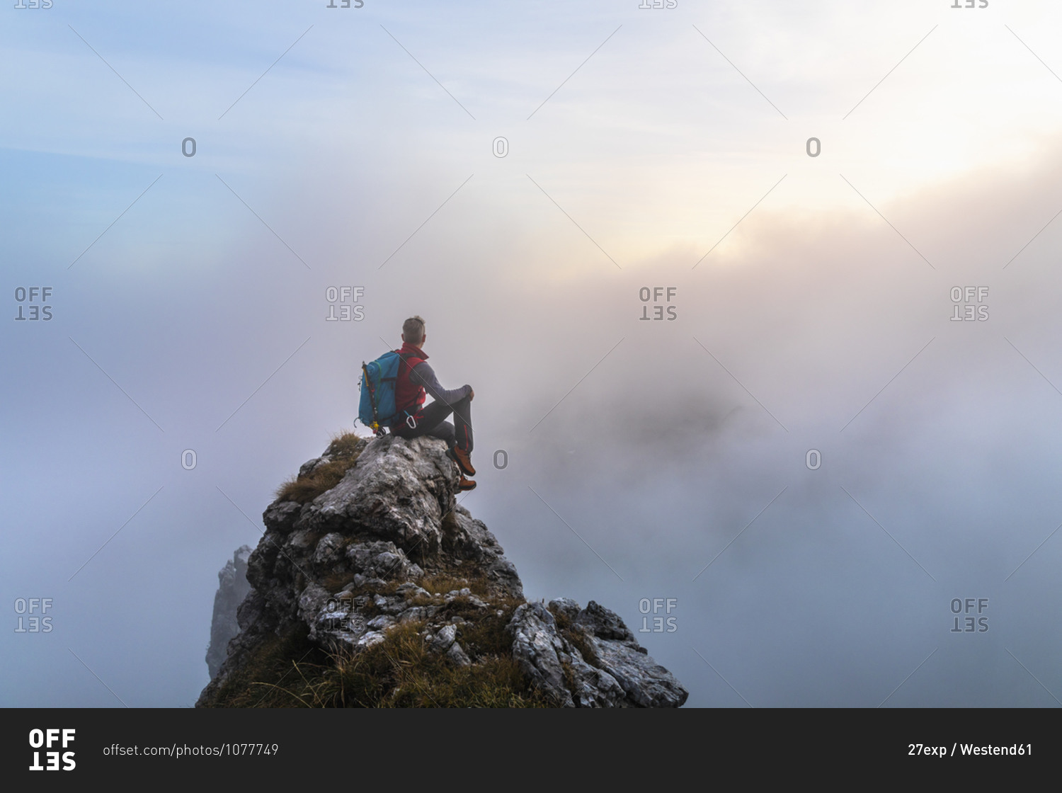 Pensive Male Hiker Sitting On Mountain Peak During Sunrise At