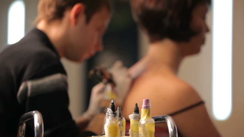 Girl gets a tattoo. Rack focus.