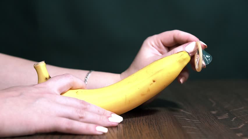 Мастурбирует бананом в презервативе