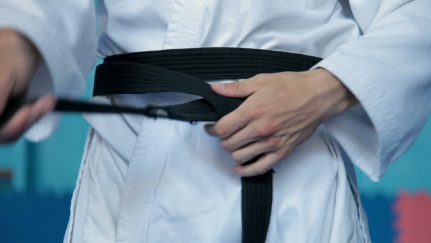 martial arts athlete tying the knot to his black belt