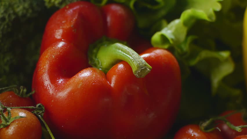 bunch of wet tomatoes, bell peppers, carrots, broccoli, garlic and other vegetables on kitchen table. Dolly shot