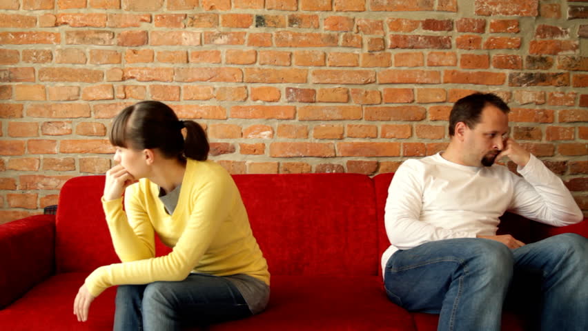 Relationship difficulties, young couple sitting on sofa apart