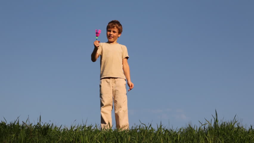boy stands on grass, little sister, clicks clapperboard and he pushes her away 