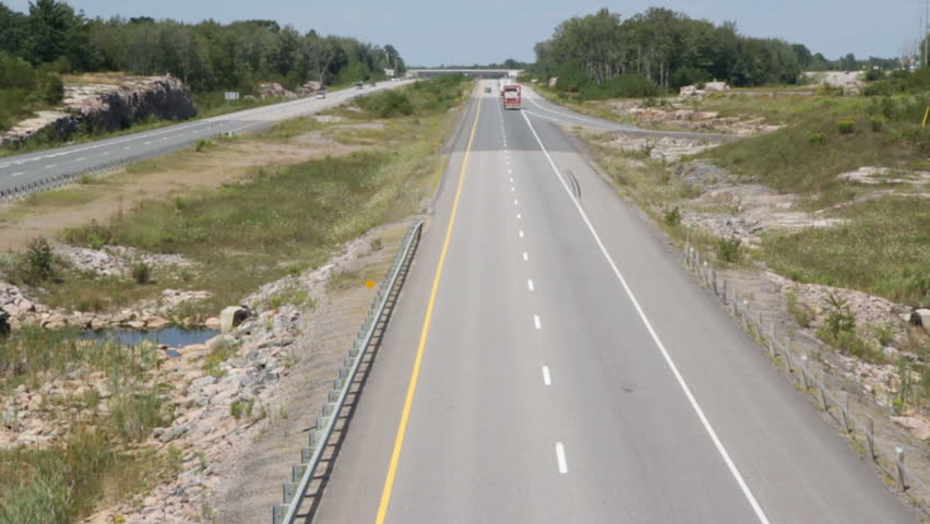 Rural highway with truck. Truck goes by with oversized load. Looking down from bridge at HWY 400 from highway 38 near Bala. Looking north. Summer in Ontario, Canada. 