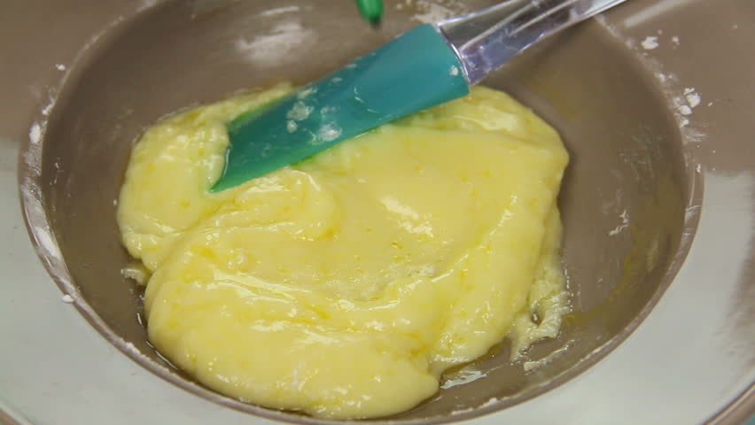 Adding food coloring to icing mixture to make it green.
