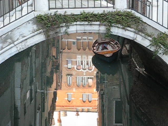 Venice: Building reflections and old wooden boat under a bridge