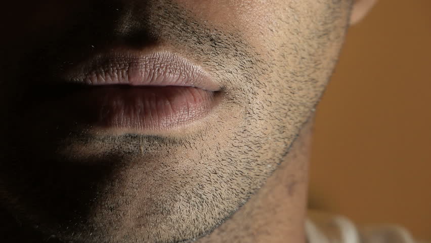 a male figure asking to keep quiet or a secret through gestures. we can only see the manÂ´s mouth in intimidating and mysterious shot